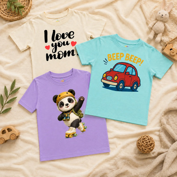 A flatlay of three kid's t-shirts arranged on a textured cream blanket alongside a woven basket, a wooden toy car, a knit bunny plush, and a woven decorative ball. The shirts include an ivory t-shirt with the text "I love you mom" and two red hearts, a spearmint t-shirt featuring a cartoon red car and the text "BEEP BEEP!", and a lavender t-shirt showing a cheerful panda wearing a yellow helmet, a backpack, and roller skates while holding binoculars.