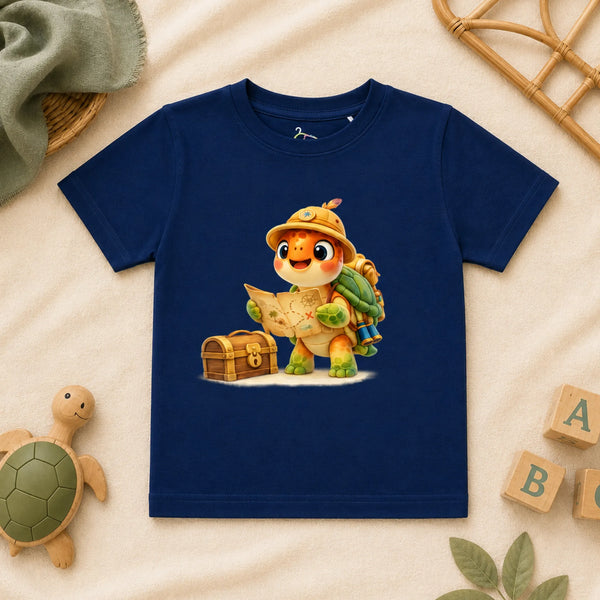 A navy blue kid's t-shirt featuring a cartoon graphic of an adventurous sea turtle wearing a safari hat and reading a treasure map next to a wooden chest