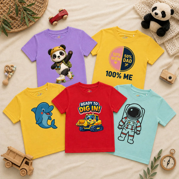 A flatlay of five kid's t-shirts arranged on a textured cream blanket alongside a woven basket, wooden toy vehicles, a plush panda, a wooden toy camera, and a wooden compass. The collection includes a lavender t-shirt showing a cheerful panda wearing a yellow helmet and roller skates, a sunshine yellow t-shirt with a split pink and navy circle graphic reading "50% MOM, 50% DAD" and "100% ME" below it, another sunshine yellow t-shirt featuring a cartoon blue dolphin, a red t-shirt displaying a yellow bulldoz