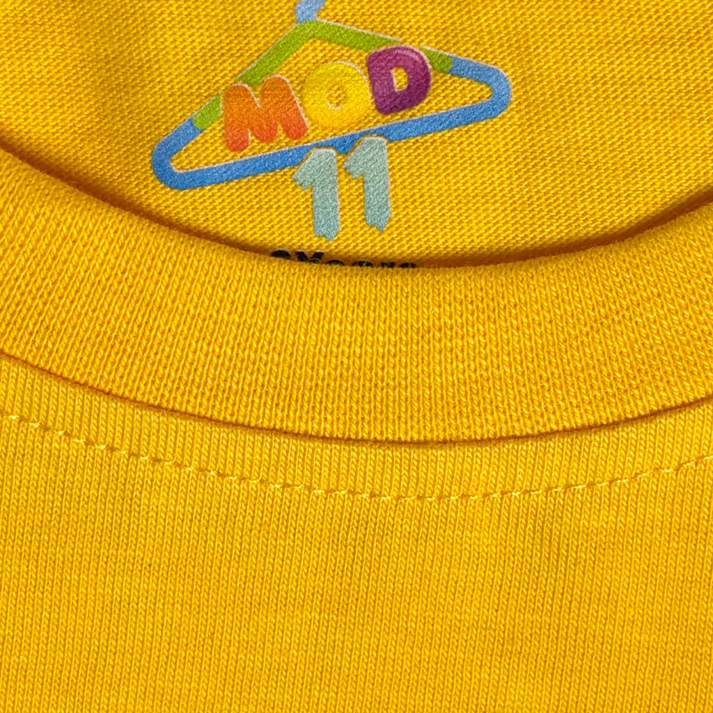 Close-up of a bright yellow knit fabric with a colorful embroidered logo reading 'MOD 11' on the upper chest. fabric-closeup