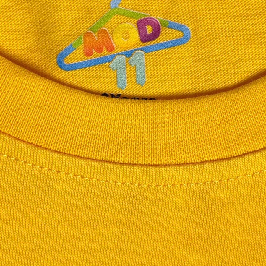 Close-up of a bright yellow knit fabric with a colorful embroidered logo reading 'MOD 11' on the upper chest. fabric-closeup